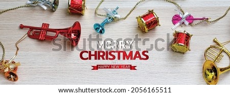 Merry Christmas and happy new year banner for head or cover of social media website or fan page decorative.       Musical instrument ornament toys for Xmas festival on wood background with texts