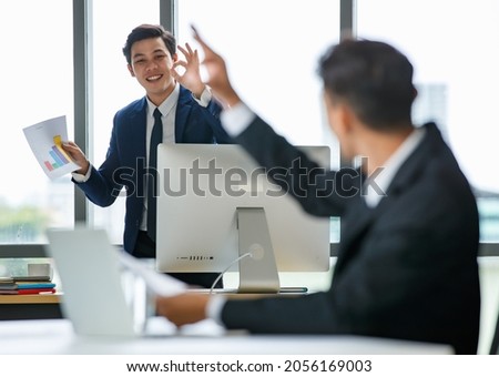 Delighted Asian businessmen showing okay signs while working in office and looking at each other