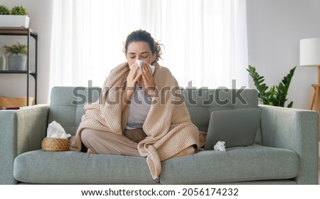 Ill upset girl is holding paper tissue and blowing nose. Virus symptom concept. Royalty-Free Stock Photo #2056174232