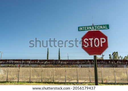 Stop sign and International Avenue street sign in front of the Mexico - United States border fencing on the United States side in Douglas, Arizona