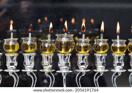 Hanukkah candles are lit in a silver menorah against the backdrop of the darkness of the night