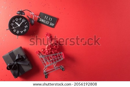 Online shopping of China, 11.11 singles day sale concept. Top view of shopping cart, black christmas gift boxes with sale card on red background with copy space.