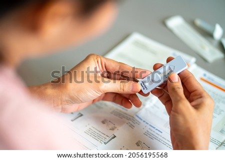 Asian woman using rapid antigen test kit for self test COVID-19 epidemic at home. Confidence female reading user manuals instruction of COVID-19 ATK . Coronavirus pandemic protection concept. Royalty-Free Stock Photo #2056195568