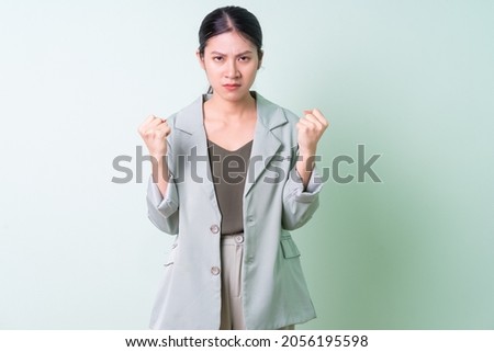Young Asian businesswoman wearing green suit on green background