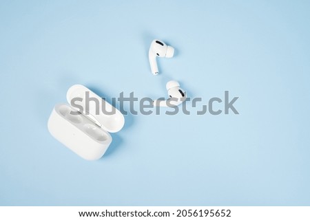 Modern wireless bluetooth headphones with charging case on a blue background.  Royalty-Free Stock Photo #2056195652