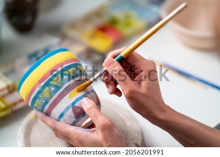 Asian woman learning color painting her self-made pottery at home. Confidence female enjoy hobbies and indoors leisure activity handicraft ceramic sculpture and painting workshop at pottery studio. Royalty-Free Stock Photo #2056201991