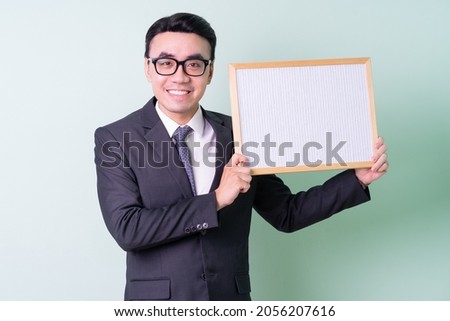 Young Asian businessman posing on green background