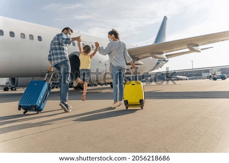 Back view of parents holding the hands of the child and going with suitcases to board the plane Royalty-Free Stock Photo #2056218686