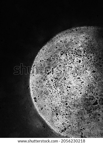An unusual relief dark dramatic pattern resembling the surface of a planet or moon. The bottom of a very old metal pan. Black and white monochrome photo.