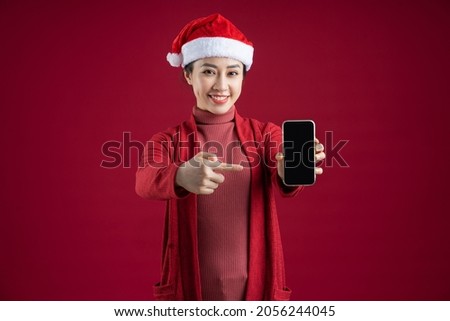 Young Asian woman wearing christmas hat on red background