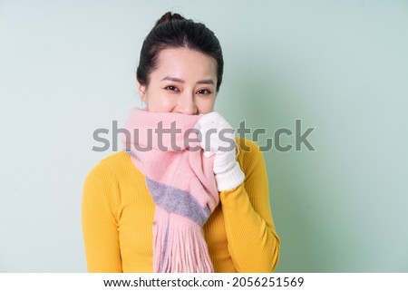 Beautiful young Asian woman wearing sweater on green background