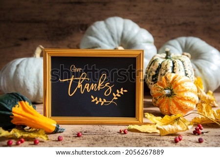 Autumn Pumpkin Decoration With English Text Give Thanks. Wooden Background with Corlorful Rustic Fall Decor Like Leaf And Golden Picture Frame