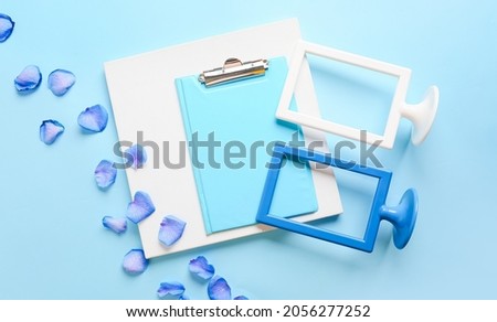 Composition with empty picture frames, poster and clipboard on color background