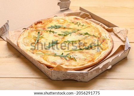 Box with tasty cheese pizza on wooden background