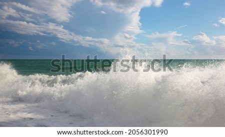 Turquoise sea with waves and foam and beautiful clouds in the sky