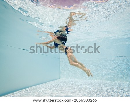 Underwater woman portrait with blue bikini inside swimming pool. Relaxing in summer time.