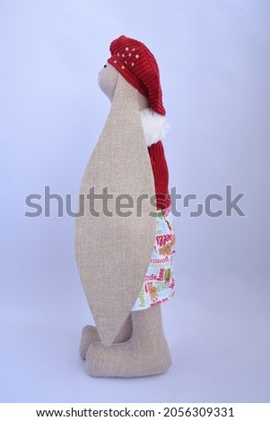 Cute Handmade textile bunny toy in beautiful Christmas dress, red velvet jacket and hat. Decorated with shiny beads and white buttons.
The background is white. 