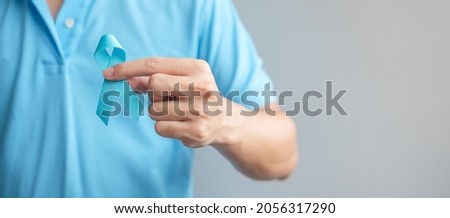 November Prostate Cancer Awareness month, Man in blue shirt with hand holding Blue Ribbon for supporting people living and illness. Healthcare, International men, Father and World cancer day concept Royalty-Free Stock Photo #2056317290