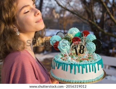 cute dreamy birthday girl holding big delicious beautiful cake with numbers 18, lollipops and marshmallows on sticks. birthday party. Celebration, congratulations, happiness, joy, pleasure