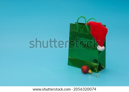 Green bag with gifts and Santa Claus hat for Christmas or New Year. Holiday gifts shopping concept.