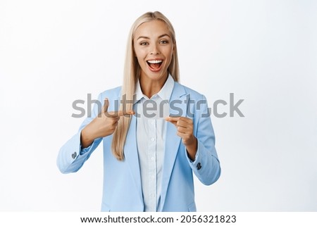 Enthusiastic businesswoman pointing and showing credit card, concept of bank advertisement, standing over white background