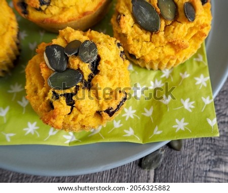 four gluten-free pumpkin muffins sprinkled with pumpkin seeds lie side by side on a green napkin on a wooden table. top view. vegan sweets