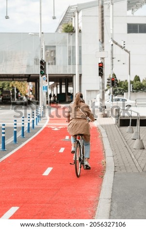 traffic, city transport and people concept - woman cycling along red bike lane with signs of bicycles and two way arrows on street in tallinn, estonia