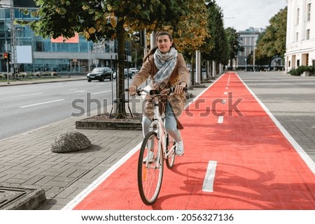 traffic, city transport and people concept - woman riding bicycle along red bike lane or two way road on street Royalty-Free Stock Photo #2056327136