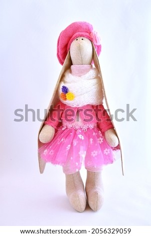 Cute Handmade textile bunny toy in beautiful pink tulle, jacket, and hat.
The background is white. 