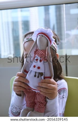 Cute Handmade textile bunny toy in chef outfit holding by a baby girl.  