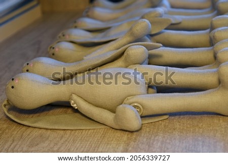Several handmade grey textile bunnies with no dress. 