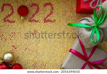 letters of the numbers 2022 from millet groats on a red background, new year and christmas poarki and christmas tree decorations, the concept of sports, fitness and diet. View from above