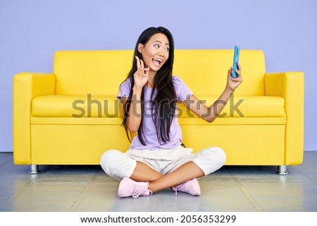 Smiling asian woman vlogger recording a video on cell phone showing victory sign. Technology, communication concept
