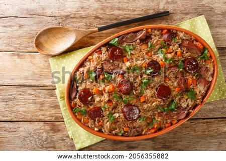 Authentic Arroz de pato duck rice is a traditional recipe from Portugal cooked with red wine, onion, carrot and chorizo close up in the baking dish on the wooden table. Horizontal top view from above
 Royalty-Free Stock Photo #2056355882