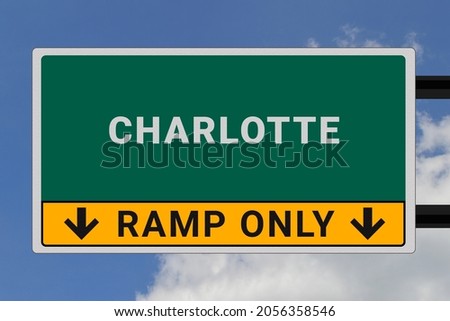 Charlotte lettering on a road sign. Signpost at the entrance to Charlotte, USA. Green pointer in American style. Road sign in the United States of America. Sky in background