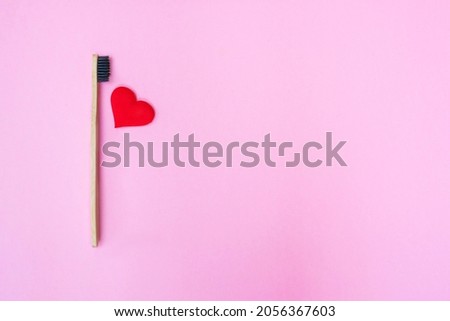 red heart and bamboo toothbrush with copy space on pink background