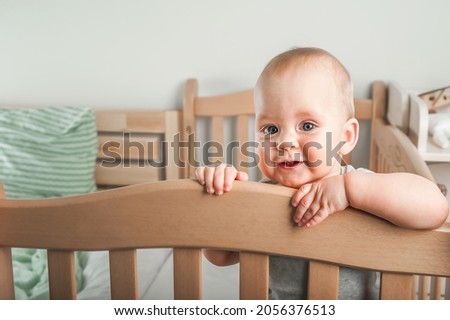 Baby 8 months on crib. Children's facial expressions, newborn care concept, healthy sleep, colic, teething.