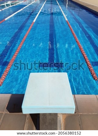 Perspective view of competition pool lanes with floating lanes and start block. Water sport, swimming and competition concept. Royalty-Free Stock Photo #2056380152