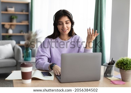 Portrait Of Smiling Woman In Headset Sitting At Table Using Pc Notebook And Talking To Webcam. Student Studying Remotely, Psychologist Working Distantly On Laptop, Consulting Clients Online Royalty-Free Stock Photo #2056384502
