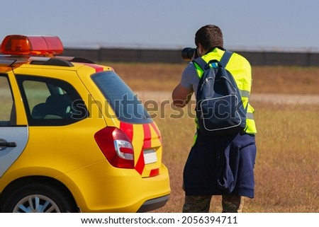 Man in yellow vest does plane spotting at the airport