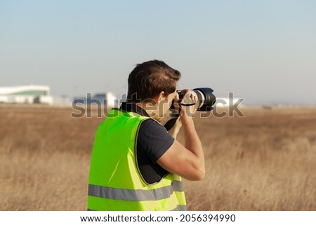 Man in yellow vest does plane spotting at the airport