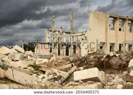 A ruined building without a roof with dismantled walls. Fragments of building structures lie in front of the building.  Selective focus.                             Royalty-Free Stock Photo #2056400375