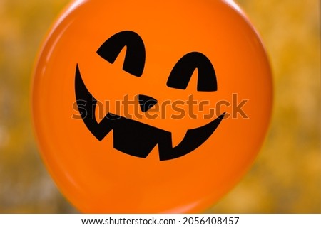 Halloween holiday decoration and party concept. A mystical orange balloon with a terrible grin