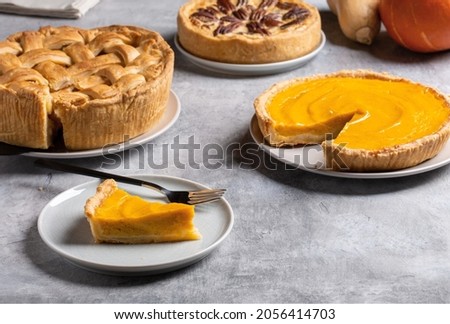 Three homemade autumn pies on gray background. Traditional American desserts. Pies with pumpkin, apple and pecan for Thanksgiving day.