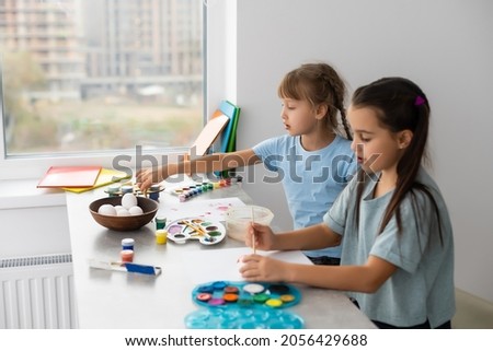 two little girls at the table with paints for drawing