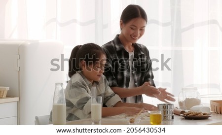Asian Mother And Little Daughter Baking Cookies Clapping Hands Having Fun With Flour Cooking Kneading Dough Together In Modern Kitchen At Home. Family Joy, Weekend Leisure Concept. Slowmo