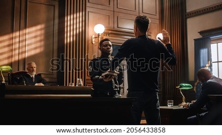 Law and Justice Court Case Witness Solemnly Swears that the Evidence He Shall Give Shall be the Truth and Nothing but the Truth Before Testifying to Lawyers and Judge in Courthouse. Royalty-Free Stock Photo #2056433858