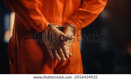 Cinematic Close Up Footage of a Handcuffed Convict at a Law and Justice Court Trial. Handcuffs on Accused Criminal in Orange Jail Jumpsuit. Law Offender Sentenced to Serve Jail Time. Royalty-Free Stock Photo #2056434935