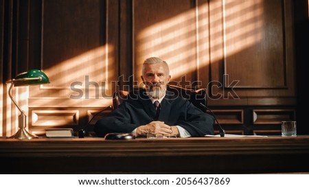 Cinematic Court of Law and Justice Trial: Portrait of Impartial Male Judge Listening To the Pleaded Case. Unbiased Decision after Hearing Arguments. Deliberation on Guilty, Not Guilty Verdict. Royalty-Free Stock Photo #2056437869