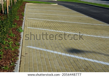new sloping parking space with drawn lines and symbols for parking wheelchair users and people with disabilities. flowerbed with hedge and lawn.